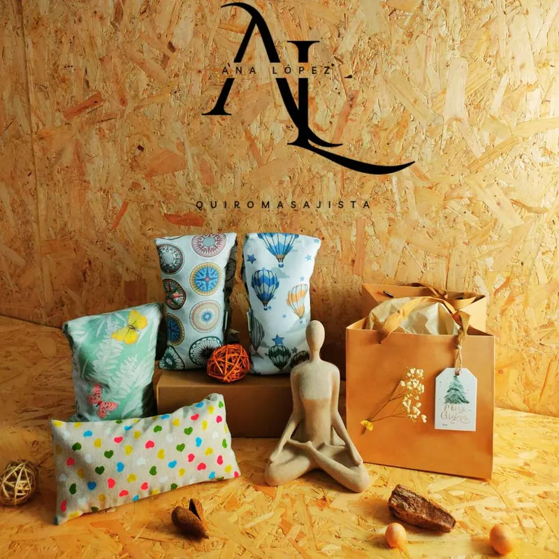 Saquitos de semillas, una figura en postura de meditación y una bolsa de regalo sobre madera, con el logotipo de Ana López